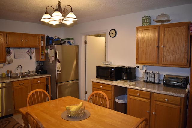 kitchen featuring pendant lighting, sink, a textured ceiling, appliances with stainless steel finishes, and a notable chandelier