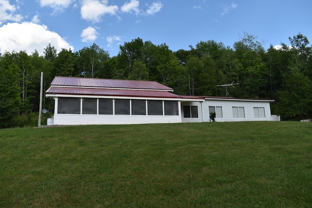 rear view of property featuring a yard and a sunroom