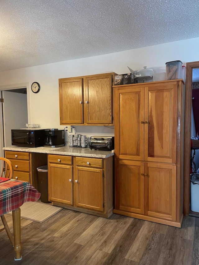 kitchen with a textured ceiling and dark hardwood / wood-style flooring