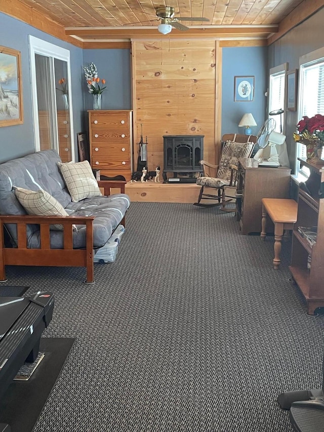 living room with a wood stove, ceiling fan, and wooden walls