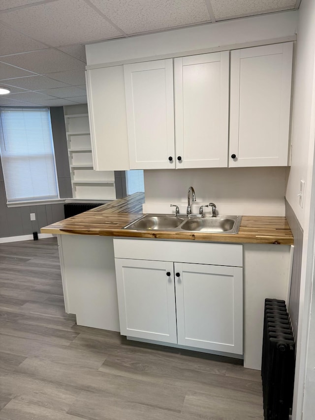 kitchen featuring sink, a paneled ceiling, white cabinetry, and radiator heating unit