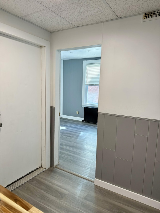 hallway with radiator, a paneled ceiling, and hardwood / wood-style floors