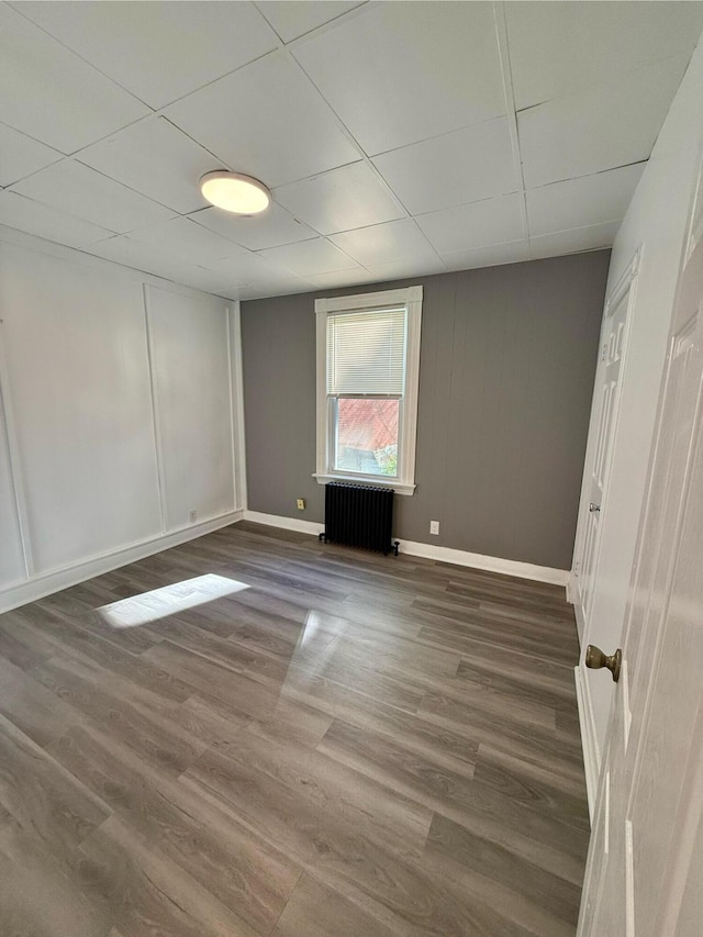 spare room with dark hardwood / wood-style flooring, a paneled ceiling, and radiator