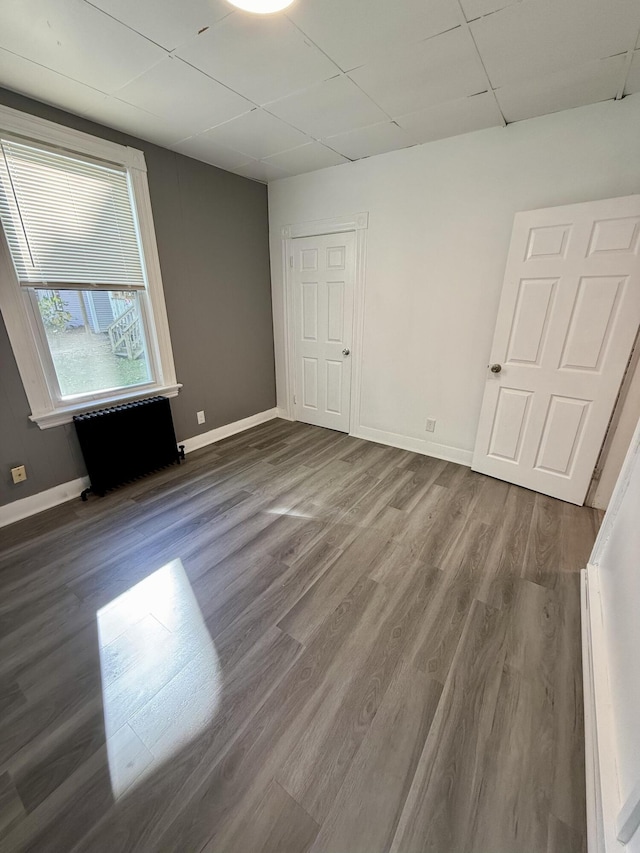 empty room featuring wood-type flooring and a drop ceiling