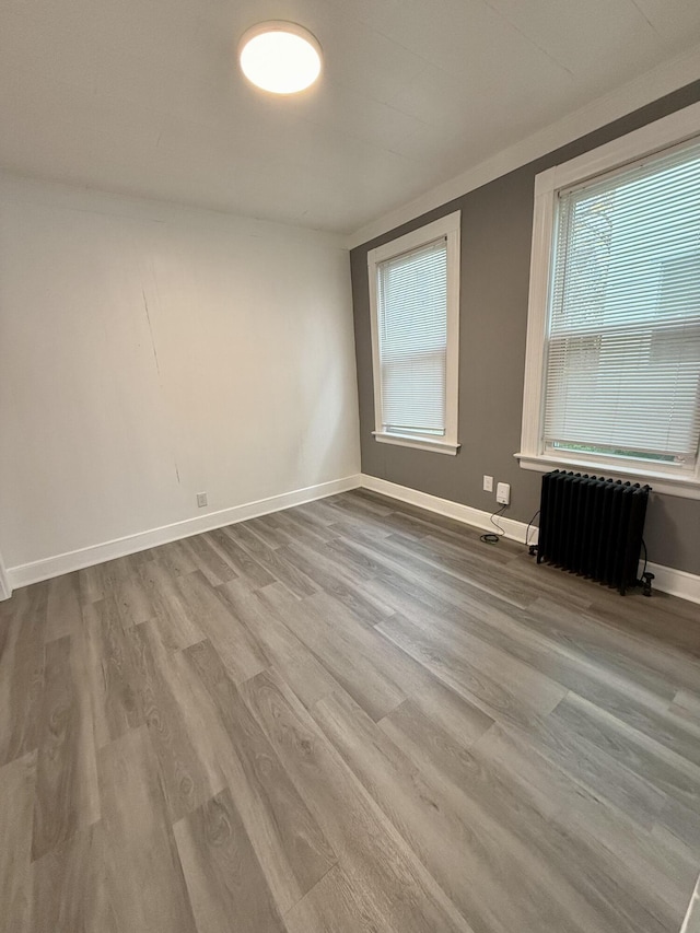 empty room with wood-type flooring and radiator