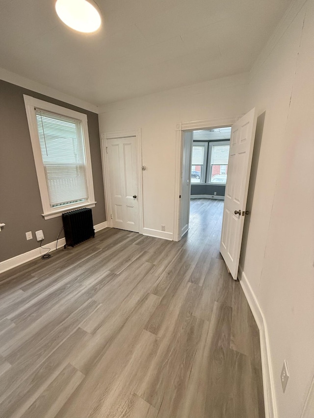 empty room with ornamental molding and light hardwood / wood-style floors