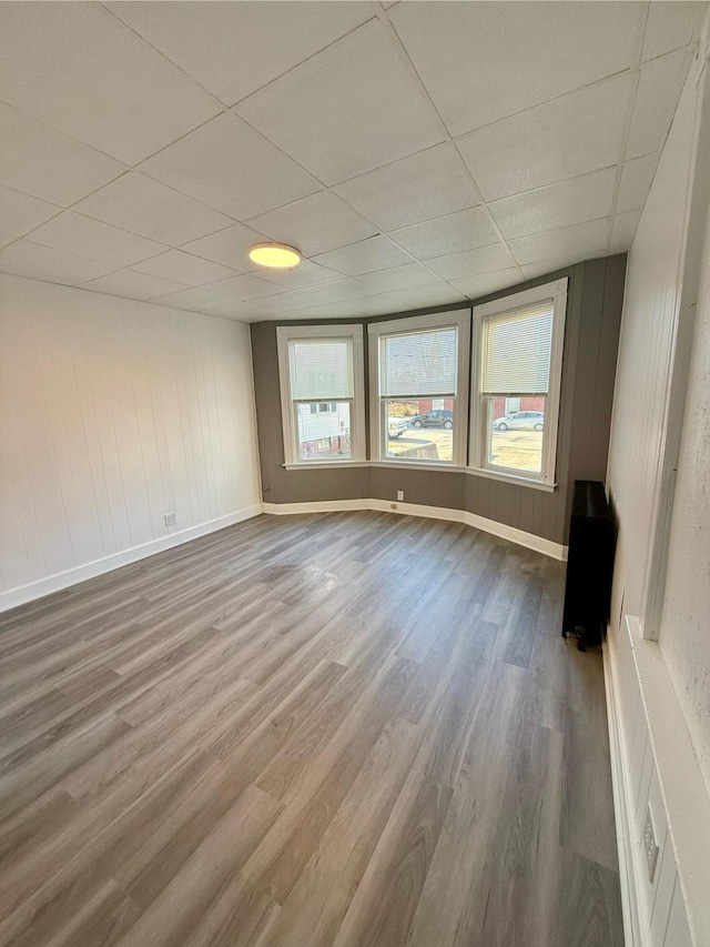 empty room with a paneled ceiling and wood-type flooring