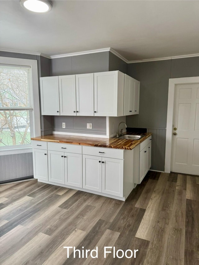 kitchen featuring white cabinets, butcher block countertops, crown molding, and sink