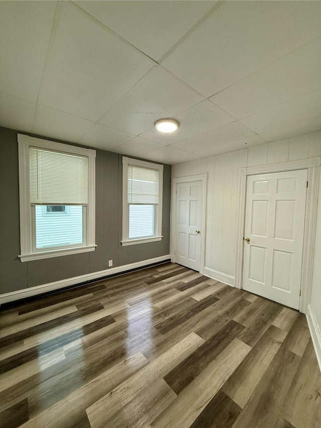 empty room featuring dark hardwood / wood-style flooring and a drop ceiling