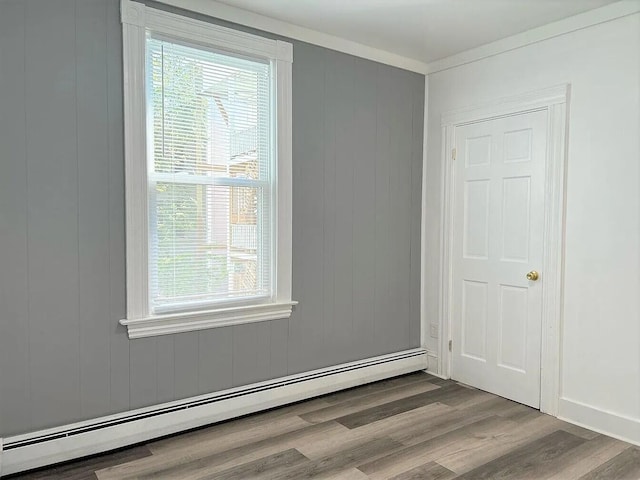 unfurnished room with baseboard heating, hardwood / wood-style flooring, and crown molding