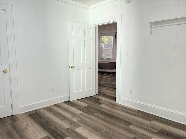 spare room with a baseboard radiator and dark wood-type flooring