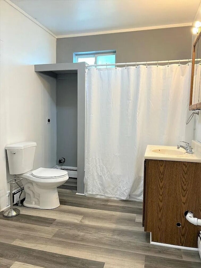 bathroom with hardwood / wood-style floors, toilet, vanity, baseboard heating, and crown molding