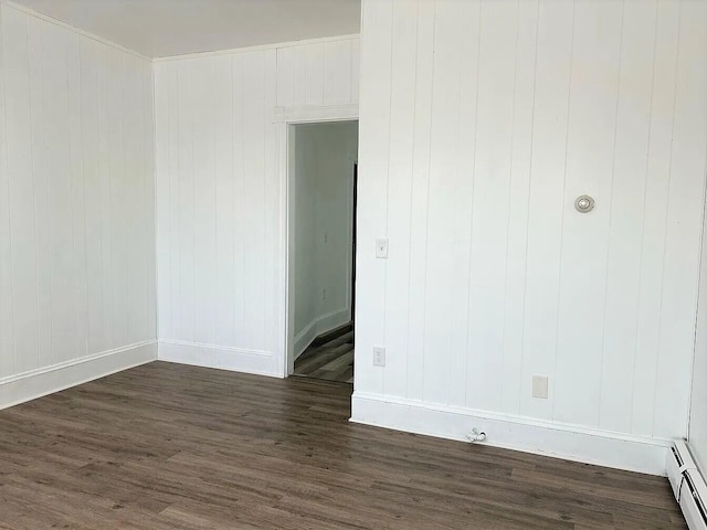 unfurnished room featuring dark hardwood / wood-style flooring and a baseboard heating unit