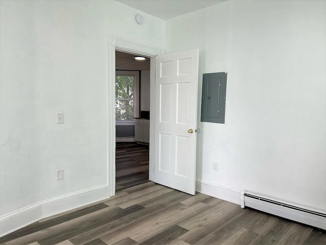 empty room with wood-type flooring, a baseboard heating unit, and electric panel