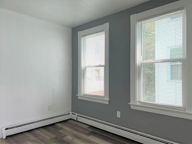 empty room featuring baseboard heating and wood-type flooring