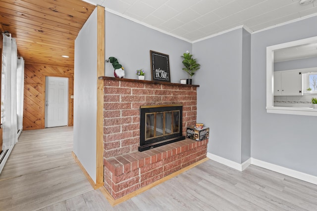 living room with wood walls, light hardwood / wood-style flooring, crown molding, and a brick fireplace