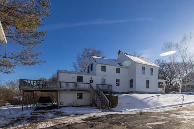 snow covered property featuring a carport and a deck