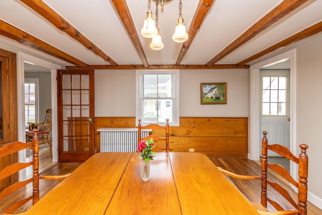 dining area featuring hardwood / wood-style floors, french doors, a healthy amount of sunlight, and an inviting chandelier