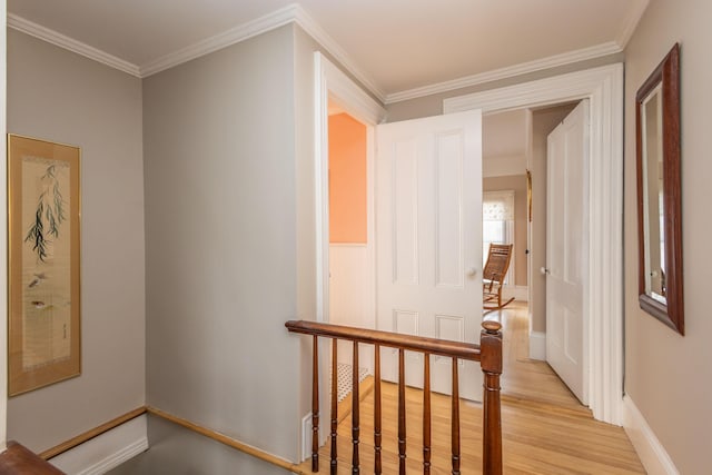 corridor with light hardwood / wood-style floors and crown molding