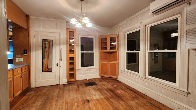 interior space featuring dark hardwood / wood-style flooring, a notable chandelier, and an AC wall unit