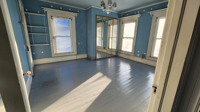 empty room featuring ornamental molding, a notable chandelier, and dark hardwood / wood-style flooring