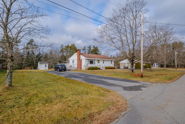 view of front of property with a front yard and a storage shed