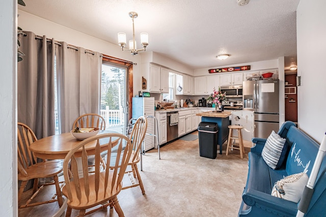 kitchen featuring a center island, a chandelier, pendant lighting, white cabinets, and appliances with stainless steel finishes