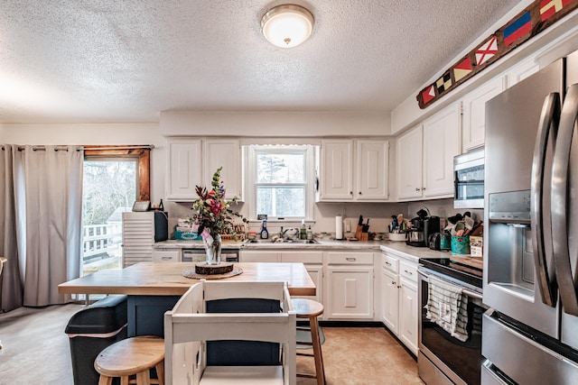 kitchen featuring white cabinets, a wealth of natural light, sink, and appliances with stainless steel finishes