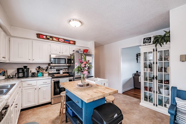 kitchen with white cabinets, a center island, butcher block counters, and appliances with stainless steel finishes