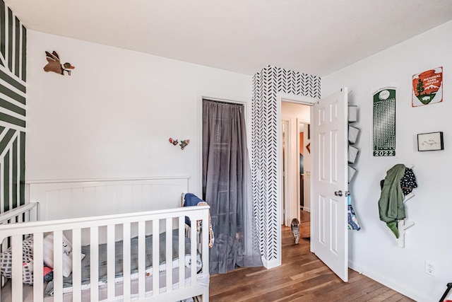 bedroom featuring a nursery area and dark wood-type flooring