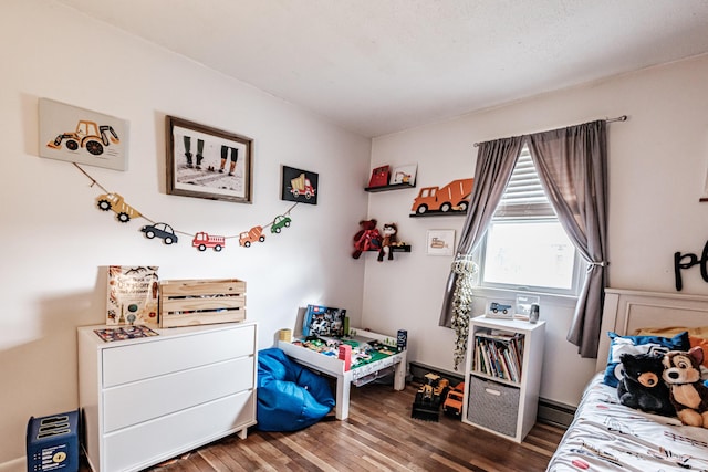 bedroom featuring hardwood / wood-style floors and a baseboard heating unit