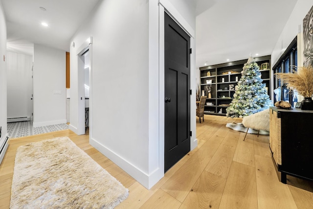 corridor with hardwood / wood-style floors, built in features, and a baseboard radiator