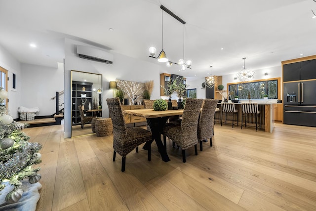 dining room featuring an AC wall unit, light hardwood / wood-style flooring, and an inviting chandelier