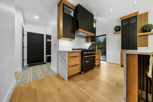 kitchen with light hardwood / wood-style flooring, custom range hood, high end black range, and tasteful backsplash