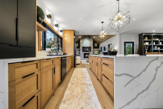 kitchen with light stone counters, decorative light fixtures, a fireplace, ceiling fan with notable chandelier, and light wood-type flooring