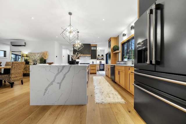 kitchen with light stone countertops, high end fridge, a spacious island, decorative light fixtures, and a chandelier