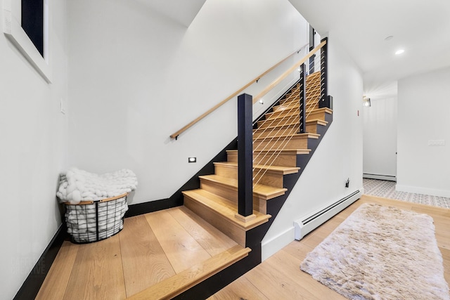 stairs featuring hardwood / wood-style flooring and a baseboard heating unit