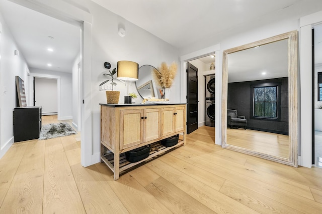 hallway with stacked washing maching and dryer and light hardwood / wood-style floors