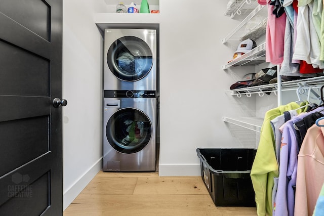 clothes washing area with light hardwood / wood-style floors and stacked washer / dryer