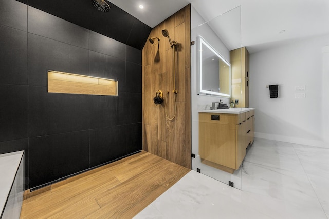 bathroom with a tile shower and vanity