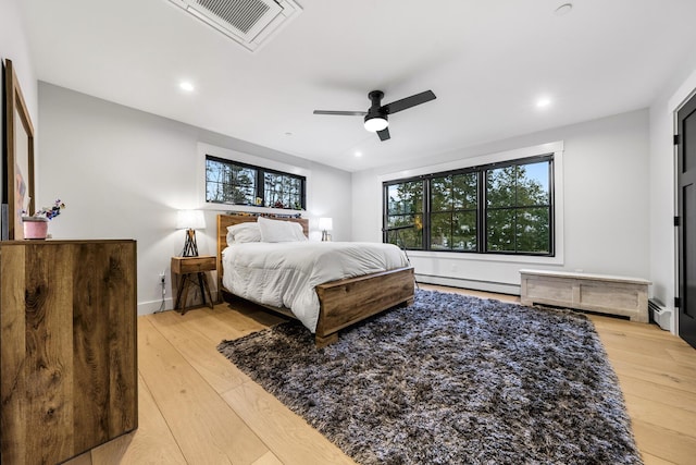 bedroom featuring light wood-type flooring, ceiling fan, and a baseboard heating unit