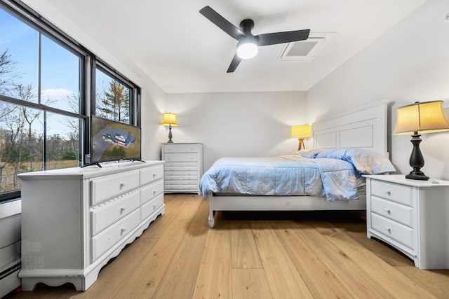 bedroom featuring light wood-type flooring, baseboard heating, and ceiling fan