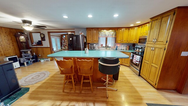 893 Horseback Rd, Levant, ME 04456 - kitchen featuring appliances with stainless steel finishes, light wood finished floors, a kitchen island, wooden walls, and a breakfast bar