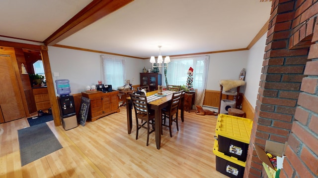 dining space with wood walls, a baseboard heating unit, ornamental molding, light hardwood / wood-style floors, and a chandelier