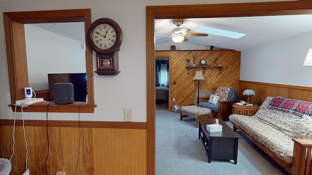 living room with light carpet, vaulted ceiling with skylight, and ceiling fan