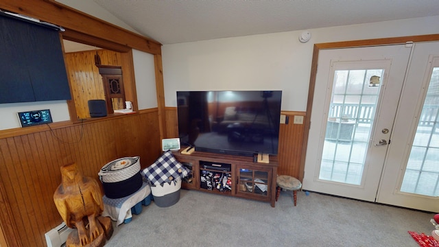 living room featuring carpet flooring, lofted ceiling, wooden walls, and a baseboard radiator