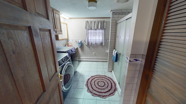 bathroom with independent washer and dryer, tile patterned floors, a baseboard heating unit, a shower with shower door, and tile walls