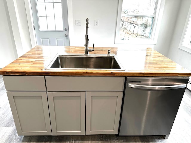 kitchen with butcher block countertops, gray cabinets, stainless steel dishwasher, and sink