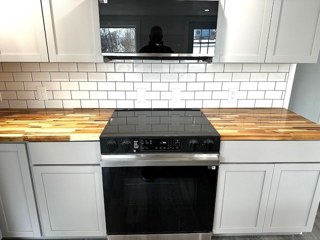 kitchen featuring ventilation hood, stainless steel electric range, tasteful backsplash, and wooden counters