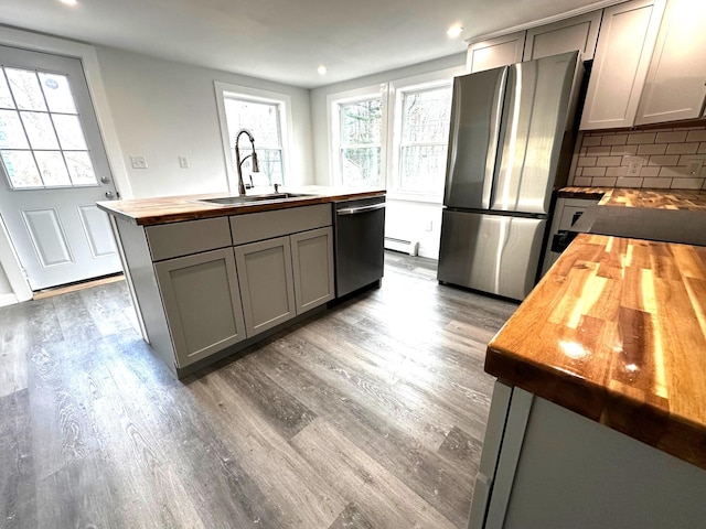 kitchen with decorative backsplash, gray cabinets, stainless steel appliances, and wooden counters